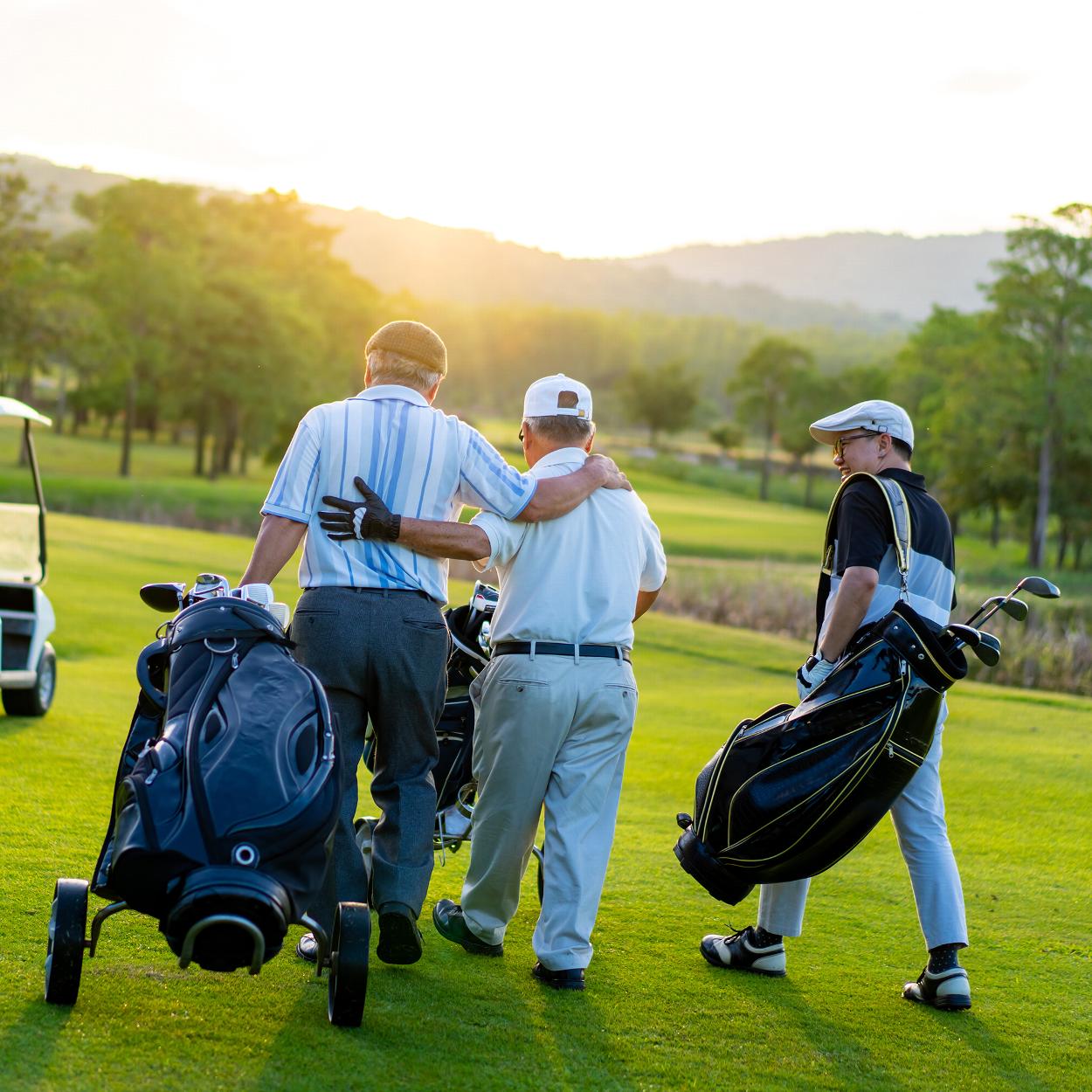 Two senior men and young man walking on golf course
